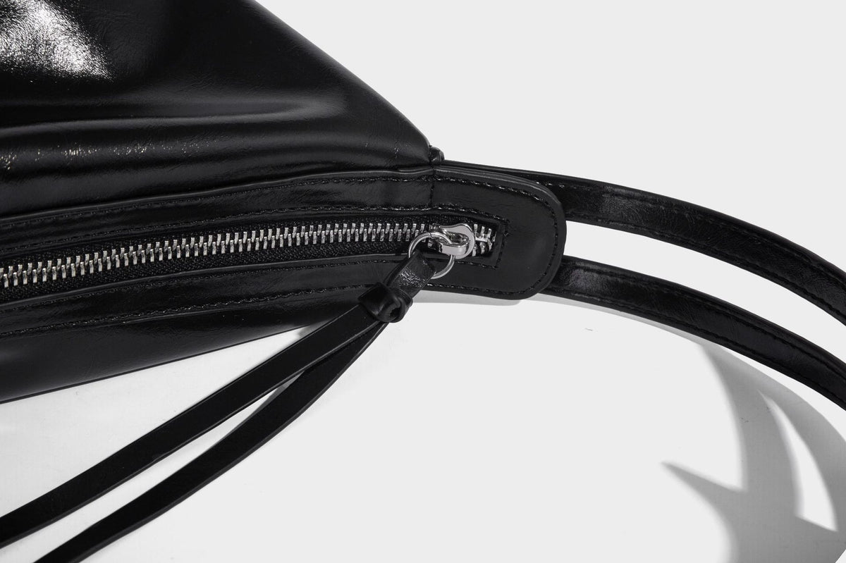 Glossy black slouchy hobo shoulder bag with zip closure, silver-tone ring hardware, and adjustable crossbody strap, detail