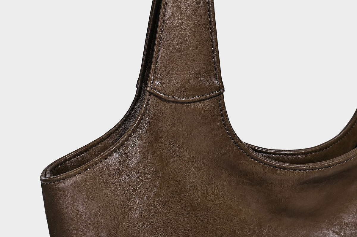 Large open-top tote bag with crinkled leather-look finish, long double shoulder straps, and embossed circular detail on