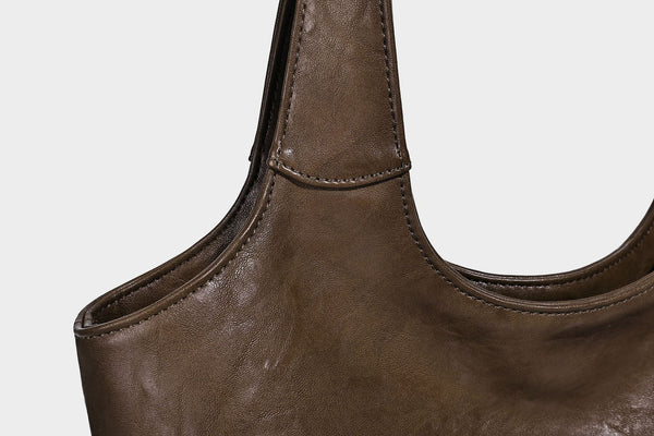 Large open-top tote bag with crinkled leather-look finish, long double shoulder straps, and embossed circular detail on