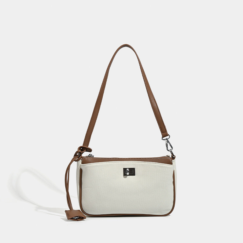 Small structured cream crossbody bag with contrast leather-look trim, silver-tone turn-lock hardware, and adjustable