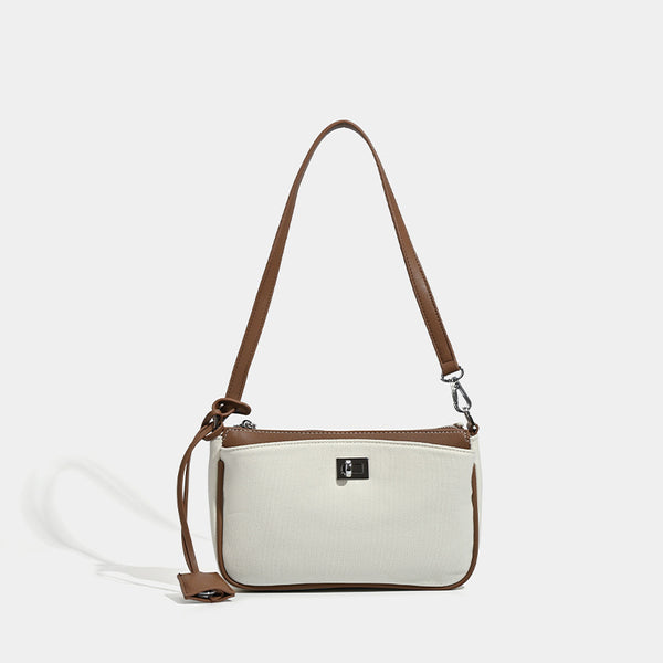 Small structured cream crossbody bag with contrast leather-look trim, silver-tone turn-lock hardware, and adjustable