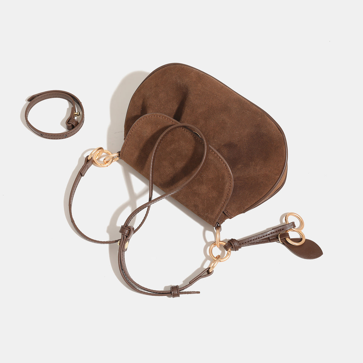 Small rounded flap crossbody saddle bag with gold-tone ring hardware and adjustable strap, detail view 4