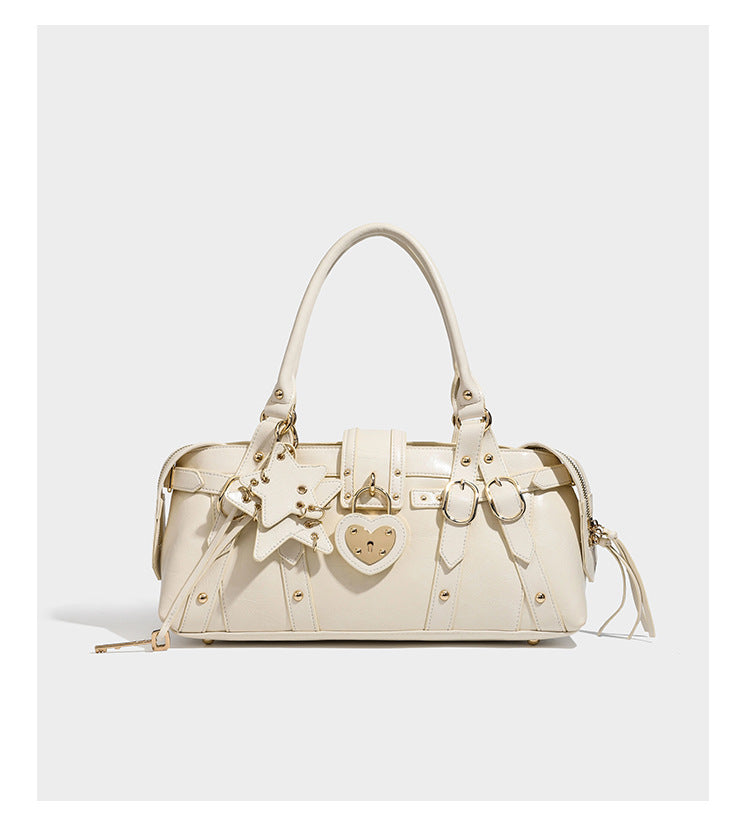 Glossy dark brown structured Boston satchel with heart-shaped lock charm, star pendant, rivet studs, multi-strap front panel