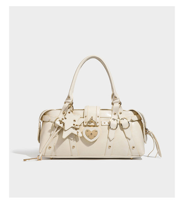 Glossy dark brown structured Boston satchel with heart-shaped lock charm, star pendant, rivet studs, multi-strap front panel