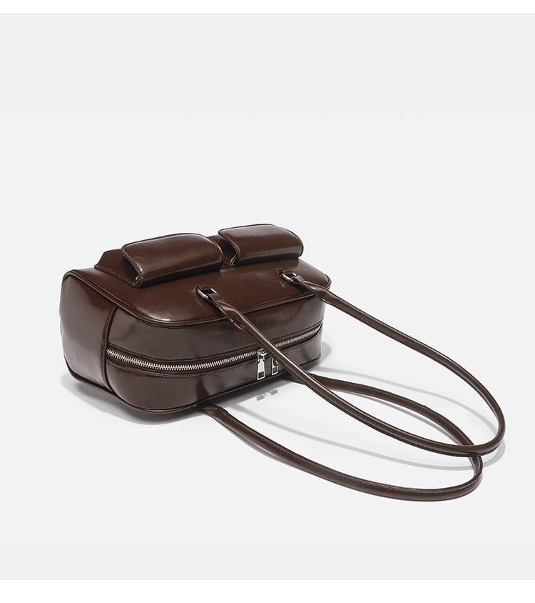 Structured glossy leather-look bowling shoulder bag with two front flap pockets, top zip closure, and long double shoulder