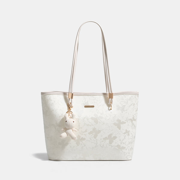 Off-white structured tote bag with dual shoulder straps, gold-tone hardware, and plush bear charm, detail view 6