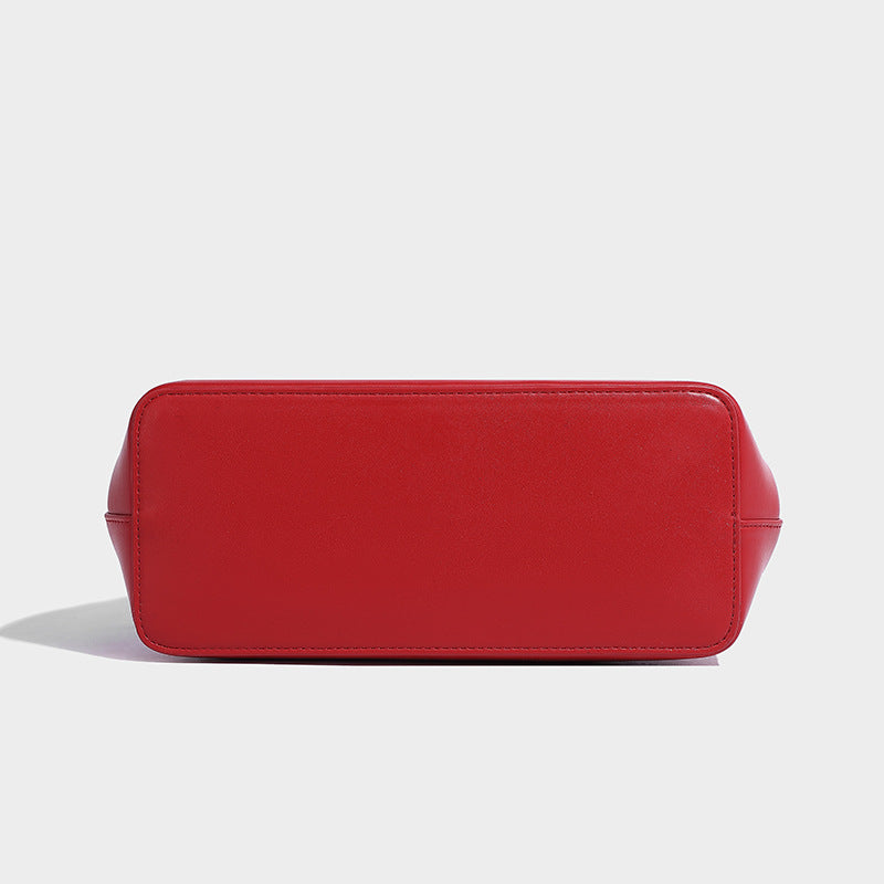 Small structured shell top-handle bag in red with heart charm and braided cord detail, smooth leather-look finish, detail
