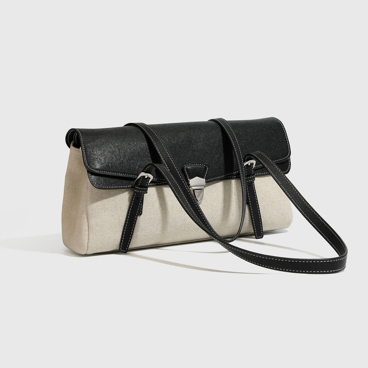 Strukturierte zweifarbige Schultertasche mit schwarzer Klappe in Lederoptik, cremefarbenem Korpus mit Webstruktur, silberfarbenem Drehverschluss und Doppel