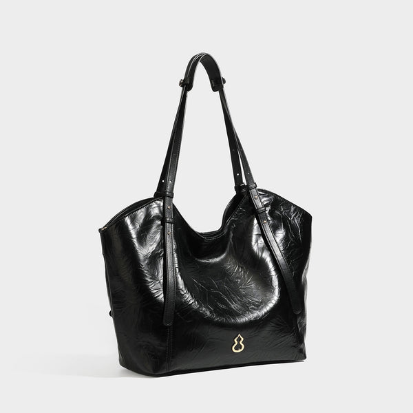 Große, glänzende Tote-Bag in geknitterter schwarzer Lederoptik mit lässiger Trapezform, zwei Schulterriemen und goldfarbenem