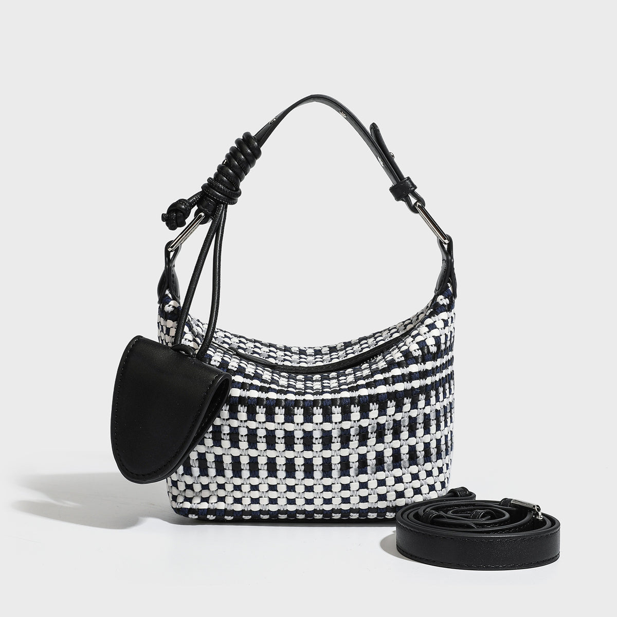 Small crescent shoulder bag in black-and-white woven textile with smooth black leather-look trim, zip-top closure, knotted