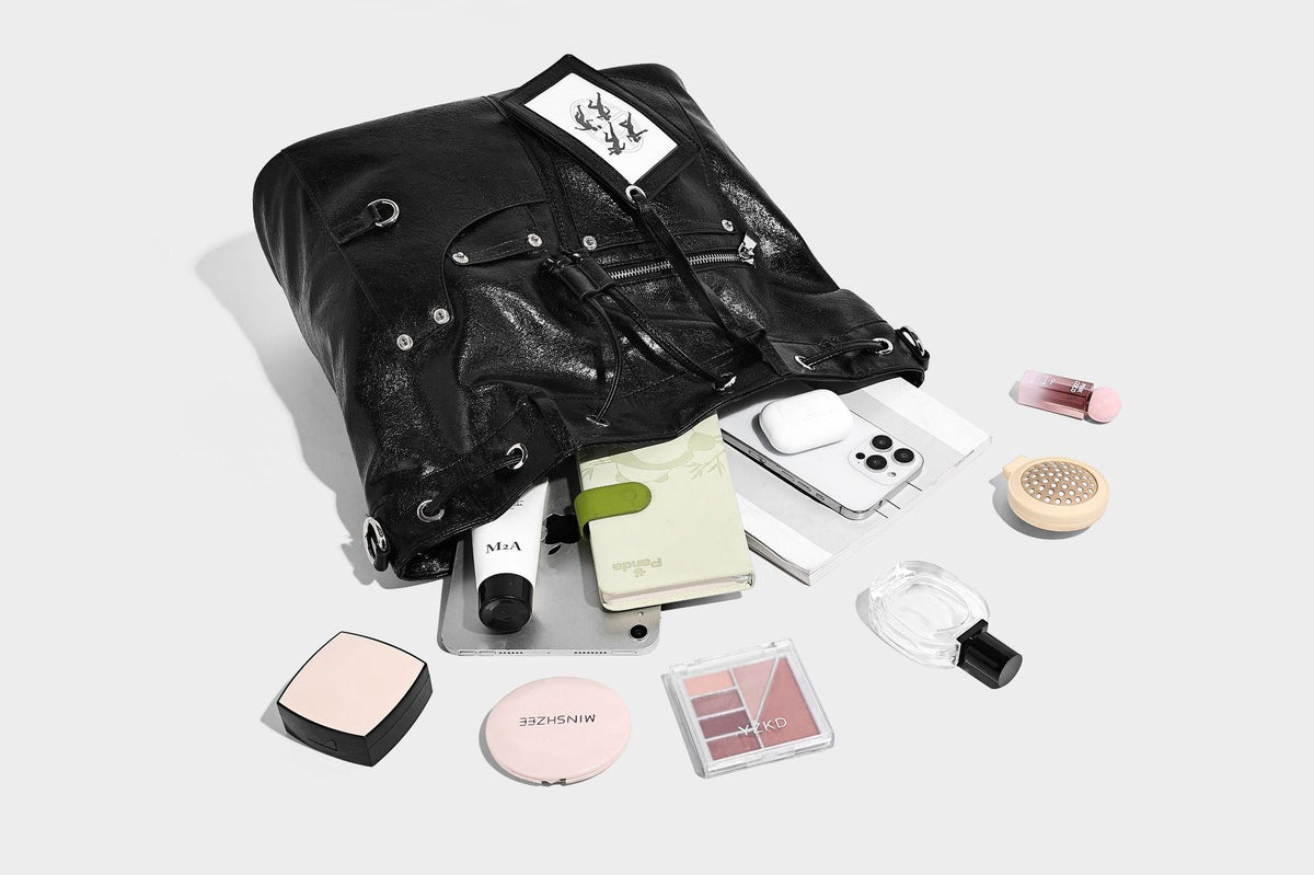 Glossy black convertible bucket backpack with silver grommet-studded straps, drawstring cinch closure, and front zip pocket