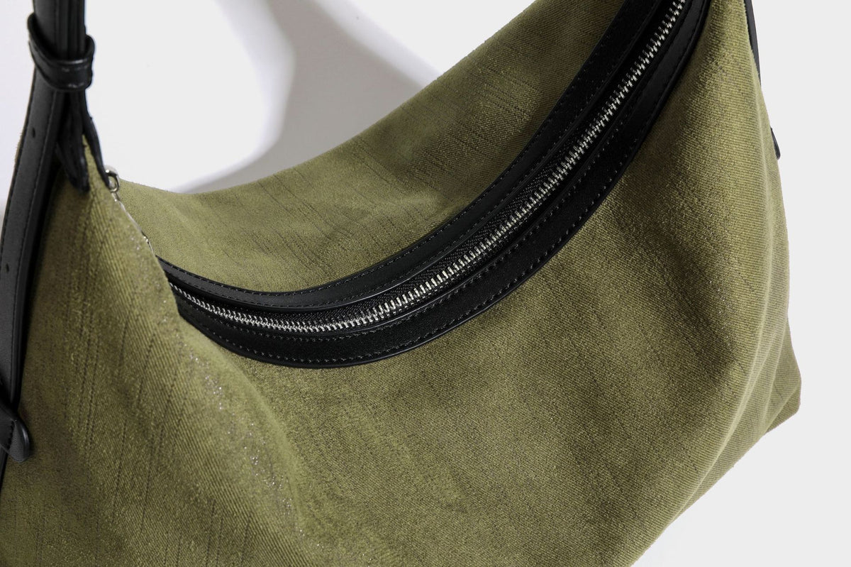 Slouchy olive green canvas hobo shoulder bag with black leather-look trim, zip-top closure, and adjustable strap, detail view