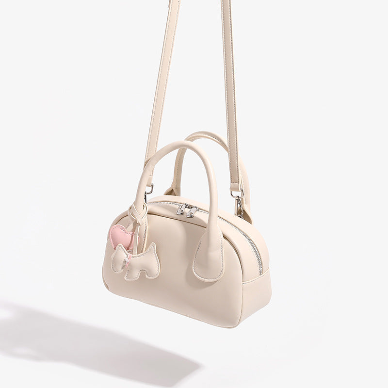 Mini-Handtasche in Kuppelform mit glatter Oberfläche in Lederoptik, zwei Tragegriffen, Reißverschluss oben, Beschlägen in Silberoptik und herabhängendem