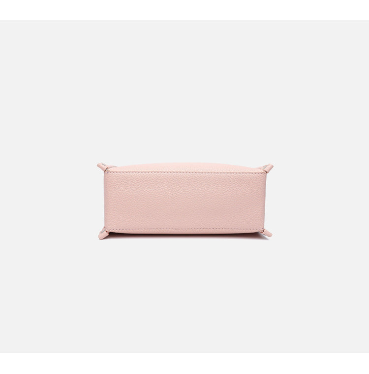 Small structured pebbled-finish convertible bag with silver corner studs, zip top, and detachable shoulder strap, detail view