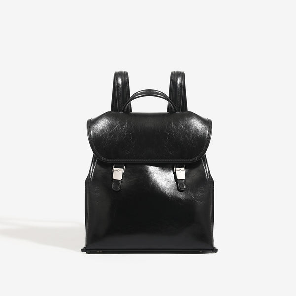 Structured glossy leather-look flap backpack handbag with dual buckle closures, top handle, and silver-tone hardware, detail
