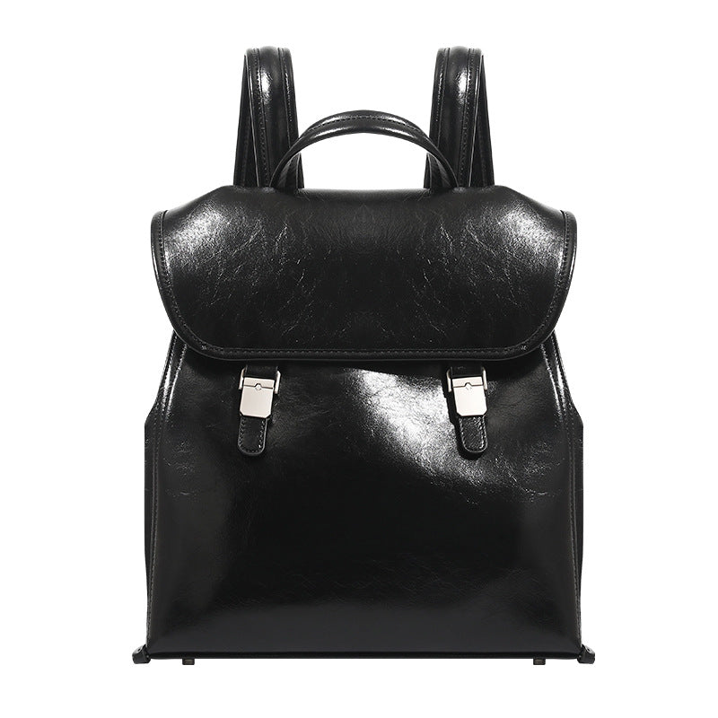 Structured glossy leather-look flap backpack handbag with dual buckle closures, top handle, and silver-tone hardware, detail