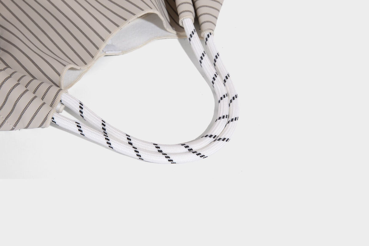 Slouchy pinstripe tote bag with braided rope handles, metal ring hardware, and colorful knotted rope charm, detail view 25