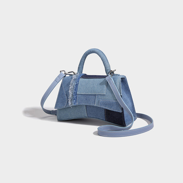 Structured patchwork denim trapezoid satchel bag with frayed panel trim, rounded top handle, and silver-tone hardware, detail
