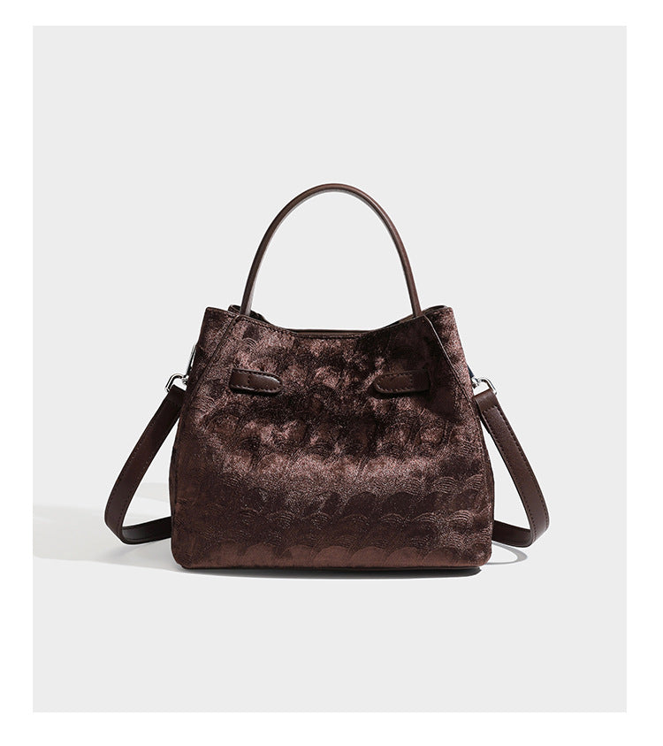 Small structured bucket satchel in embossed velvet-texture fabric with silver turn-lock hardware, rounded top handle, and