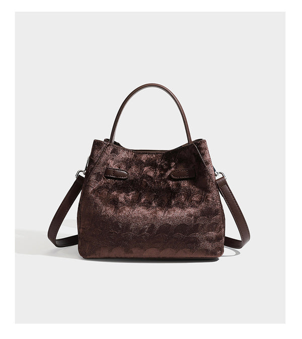 Small structured bucket satchel in embossed velvet-texture fabric with silver turn-lock hardware, rounded top handle, and