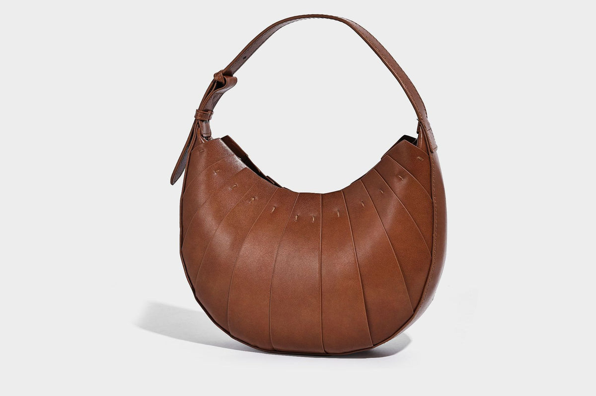 Crescent half-moon shoulder bag with vertical panel seaming, matte-satin leather-look finish, and adjustable gold-tone