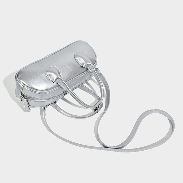 Kompakte silberfarbene Mini-Boston-Tasche mit zwei Tragegriffen oben, silberfarbenen Metallelementen und abnehmbarem Crossbody-Riemen, Detailansicht