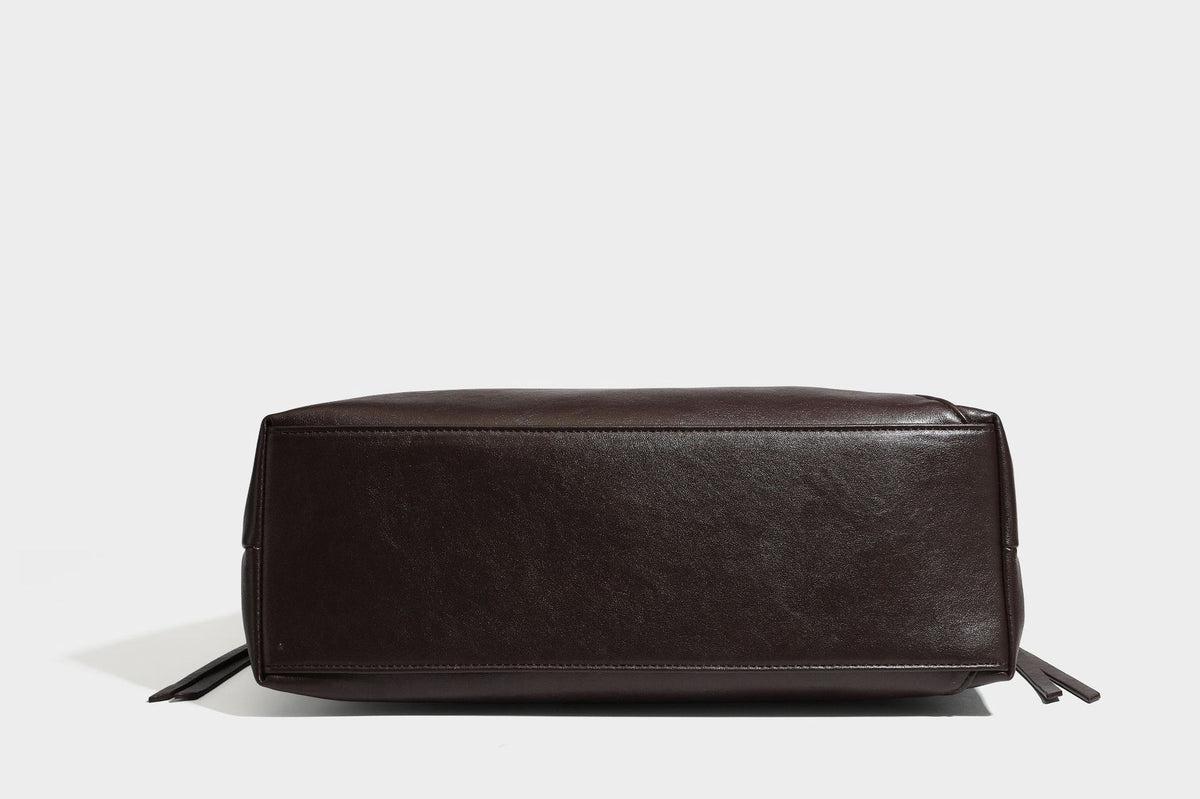 Large slouchy hobo shoulder bag with braided top handle, smooth glossy leather-look finish, and silver-tone ring hardware