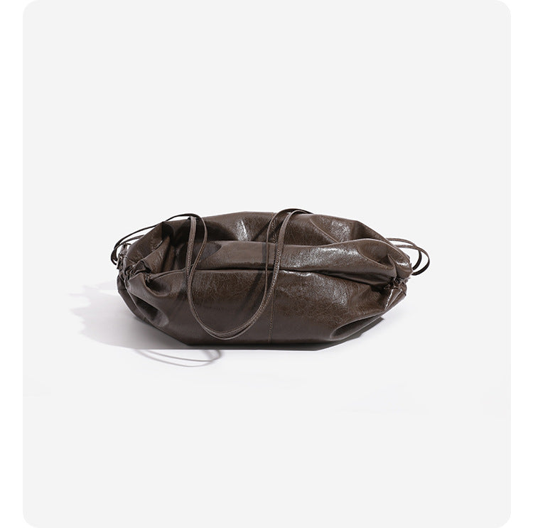 Oversized slouchy hobo shoulder bag with glossy crinkled leather-look finish, drawstring gathered sides, and silver-tone