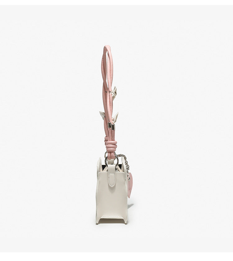 Small structured scalloped-edge shoulder bag with bow-tied pink cord strap and silver heart charm pendant, detail view 11