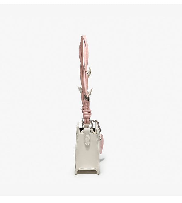 Small structured scalloped-edge shoulder bag with bow-tied pink cord strap and silver heart charm pendant, detail view 11
