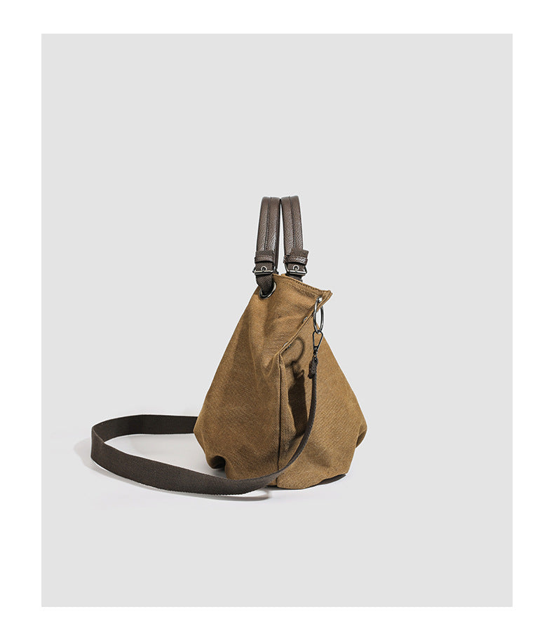 Slouchy matte canvas tote bag with dark dual top handles, metal grommet hardware, and detachable long shoulder strap, detail