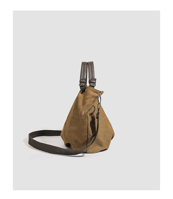 Slouchy matte canvas tote bag with dark dual top handles, metal grommet hardware, and detachable long shoulder strap, detail