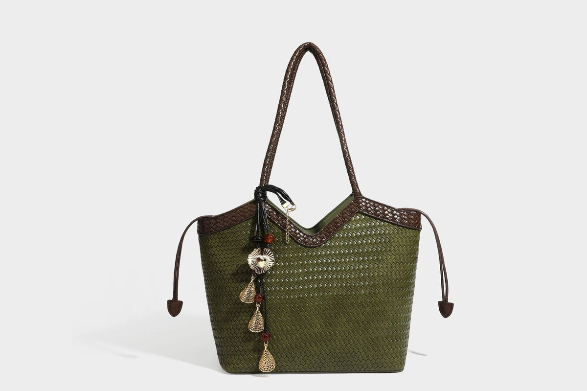 Olivgrüne Tote-Bag in Korbgeflecht-Optik mit dunkelbraunen geflochtenen Schulterriemen, seitlichen Kordelzügen und Perlenanhänger in Goldoptik