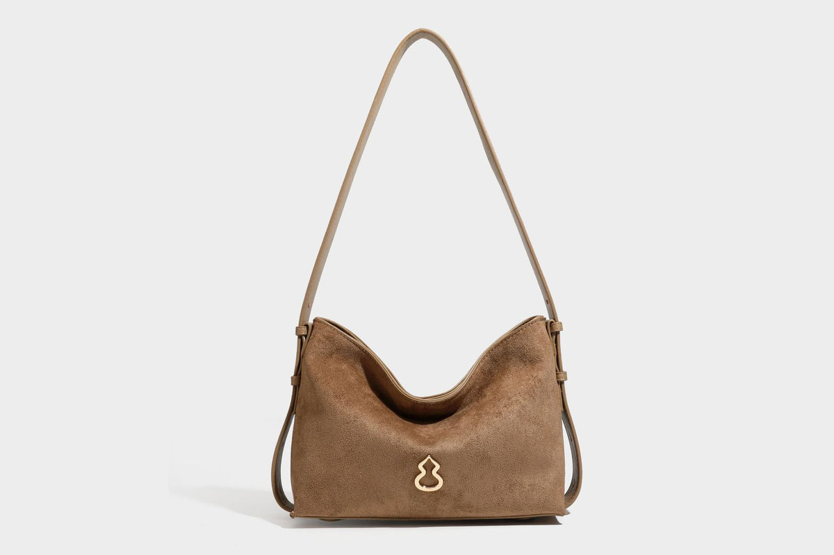 Slouchy suede-finish brown shoulder bag with long single strap and small gold-tone logo emblem on front, detail view 40