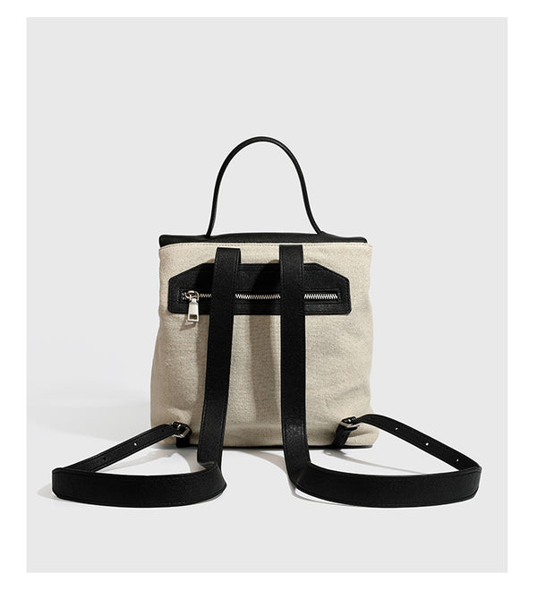 Strukturierter beigefarbener Rucksack aus gewebtem Canvas mit schwarzer Klappe in Lederoptik, Drehverschluss, Tragegriff und flachem Schulter