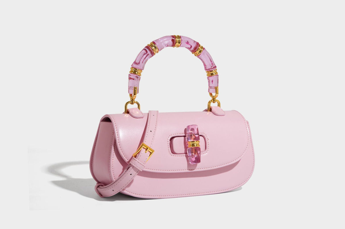 Kleine strukturierte Satteltasche mit transparentem rosafarbenem Henkel aus Harz in Bambusoptik, passendem Drehverschluss auf der Vorderseite, goldfarbenem