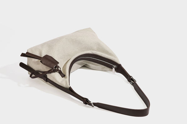 Lässige Hobo-Schultertasche aus haferfarbenem Canvas mit dunkelbraunen Besätzen in Lederoptik, silberfarbenem Reißverschluss und langem, verstellbarem
