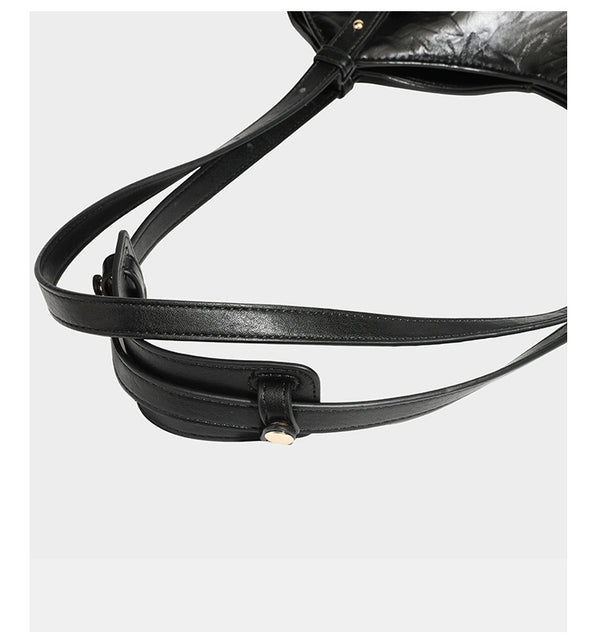 Große, glänzende Tote-Bag aus schwarzem Lederimitat mit geknitterter Optik, lässig fallender Trapezsilhouette, zwei Schulterriemen und goldfarbenen