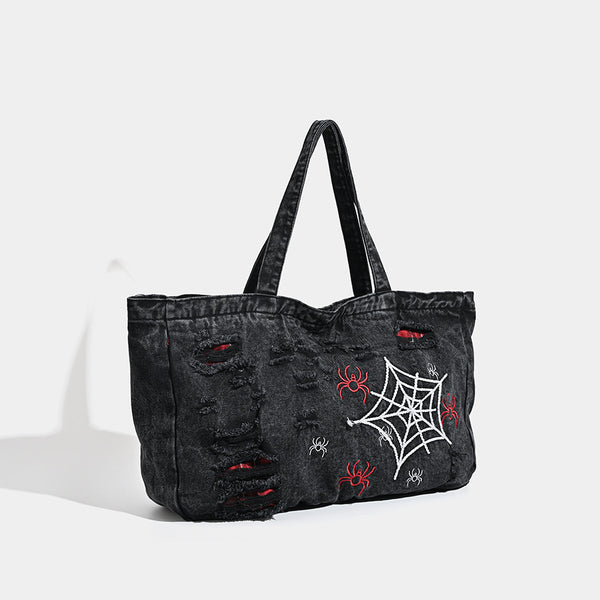 Large washed black distressed denim tote bag with white spider web embroidery and red spider motifs on the front panel