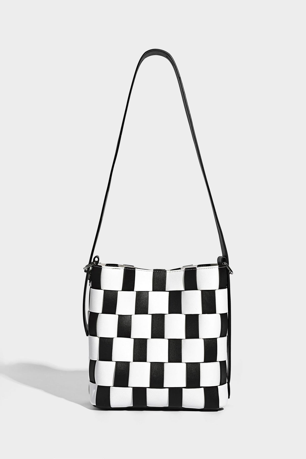 Hand-woven black-and-white checkerboard bucket bag with smooth black trim, silver-tone ring hardware, and adjustable