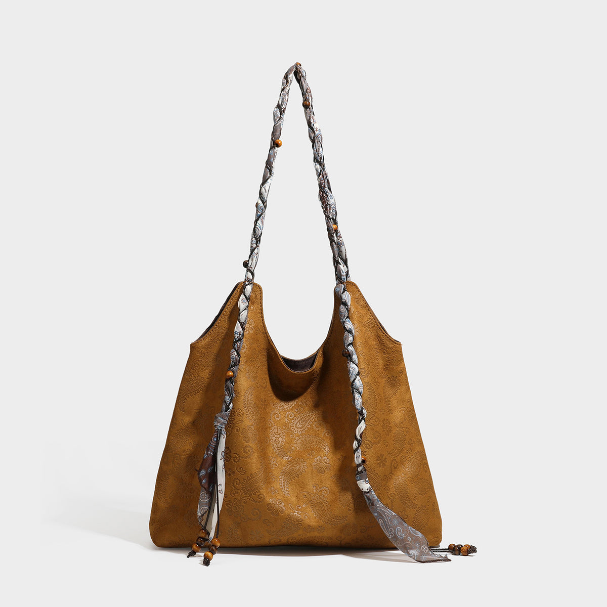 Slouchy paisley-embossed suede-look shoulder tote bag with braided patterned fabric straps and wood bead accents, detail view