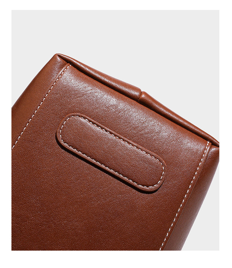 Structured smooth leather-look tote bag with long shoulder strap, gold-tone hardware, and hanging tassel-coin charm, detail