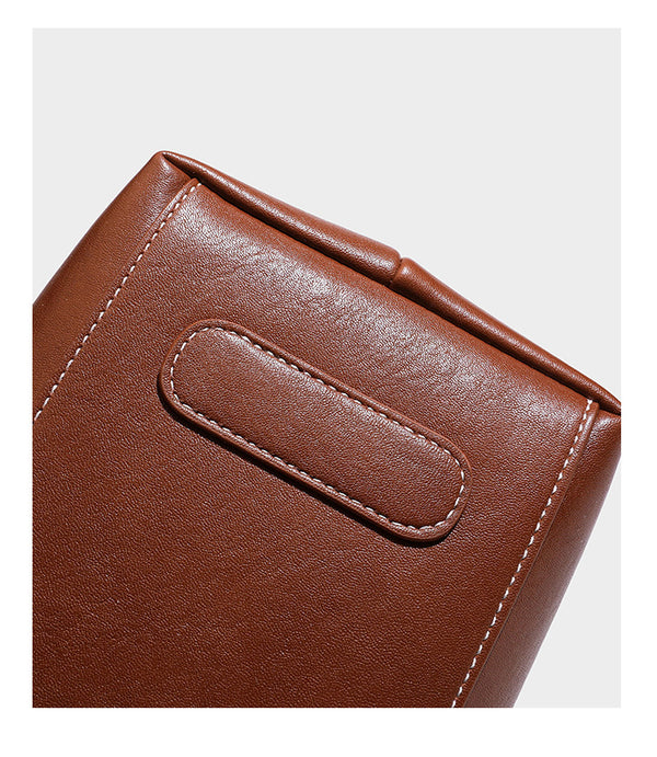 Structured smooth leather-look tote bag with long shoulder strap, gold-tone hardware, and hanging tassel-coin charm, detail