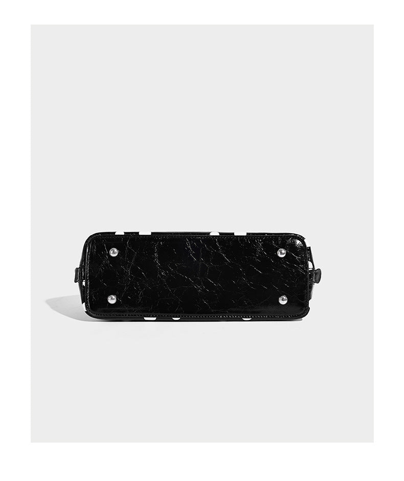 Structured polka-dot Boston bag with glossy crinkled finish, dual top handles, silver-tone turn-lock clasp, and detachable