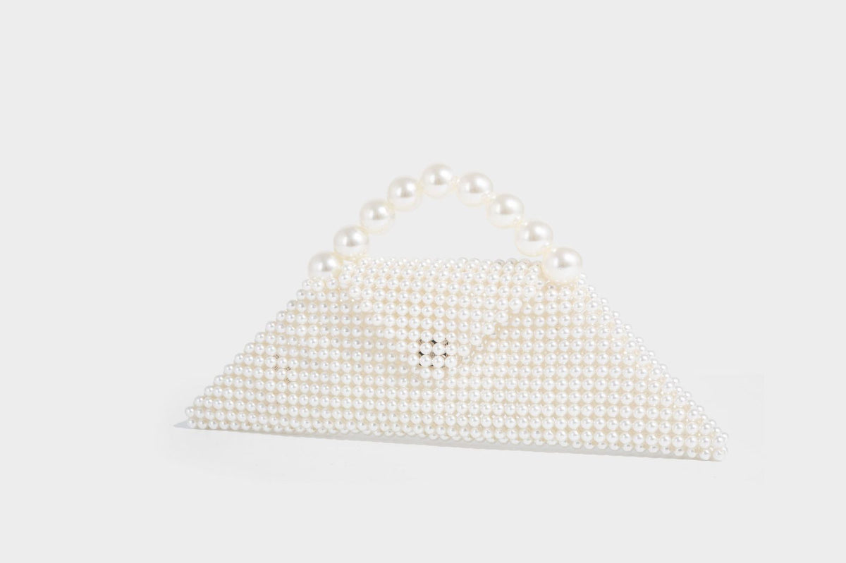Small structured triangle clutch bag covered in glossy pearl beads with an arched pearl top handle and silver snap closure