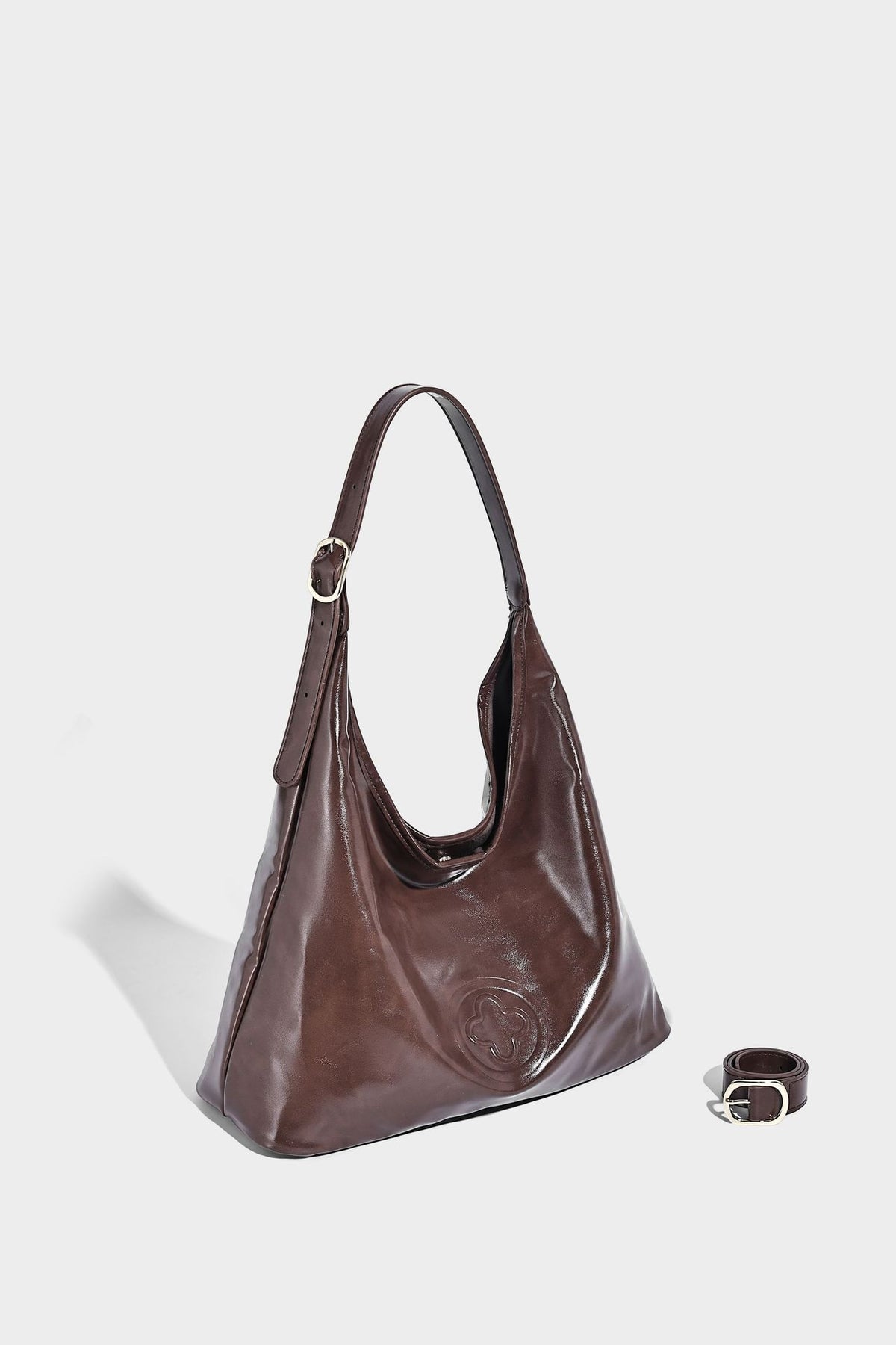 Glossy slouchy hobo shoulder bag with adjustable strap and embossed floral emblem, detail view 18