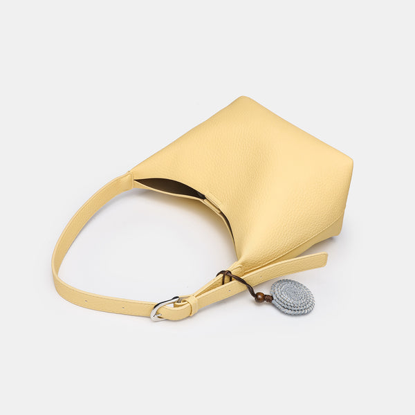 Slouchy hobo shoulder bag in pale yellow pebbled texture with woven charm, adjustable strap, matching zip pouch, and, detail