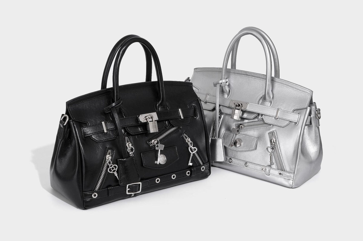 Structured black leather-look satchel bag with silver padlock hardware, front zip pockets, key charms, and top handles
