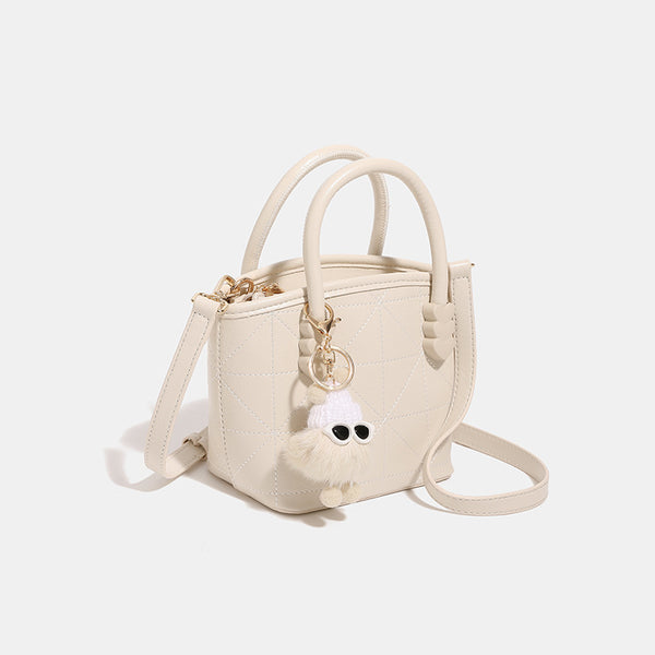 Quilted leather-look mini bucket tote bag with heart-shaped side accents, gold-tone hardware, fuzzy character charm, and