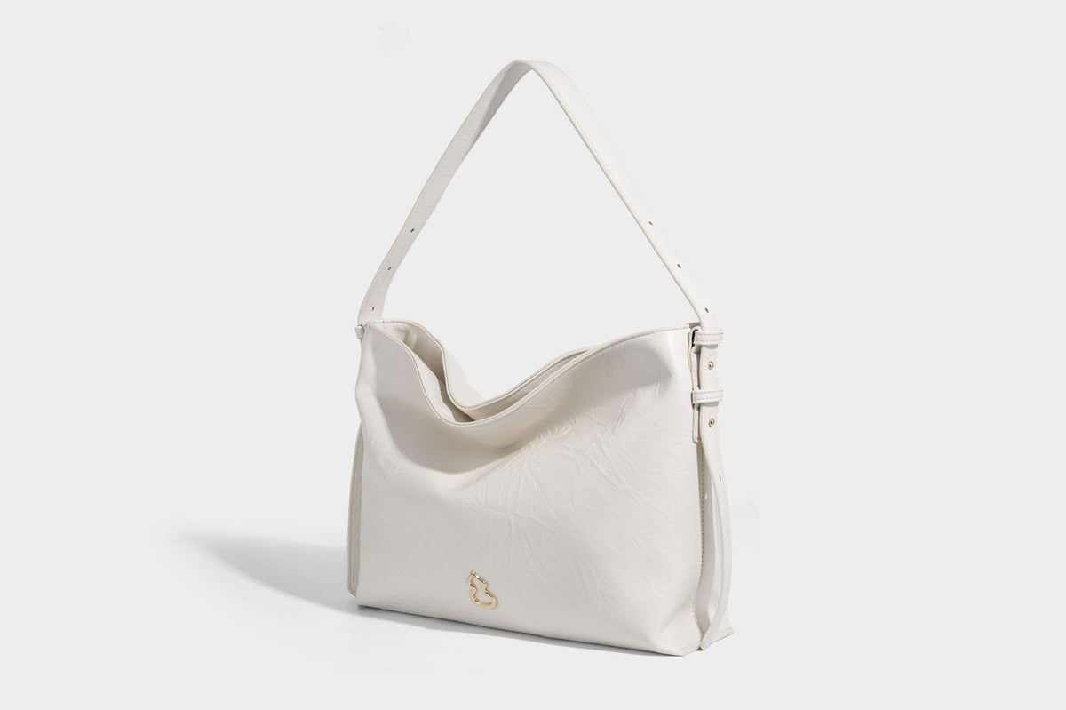 Large slouchy hobo shoulder bag in glossy crinkle leather-look finish with gold-tone emblem hardware and adjustable strap